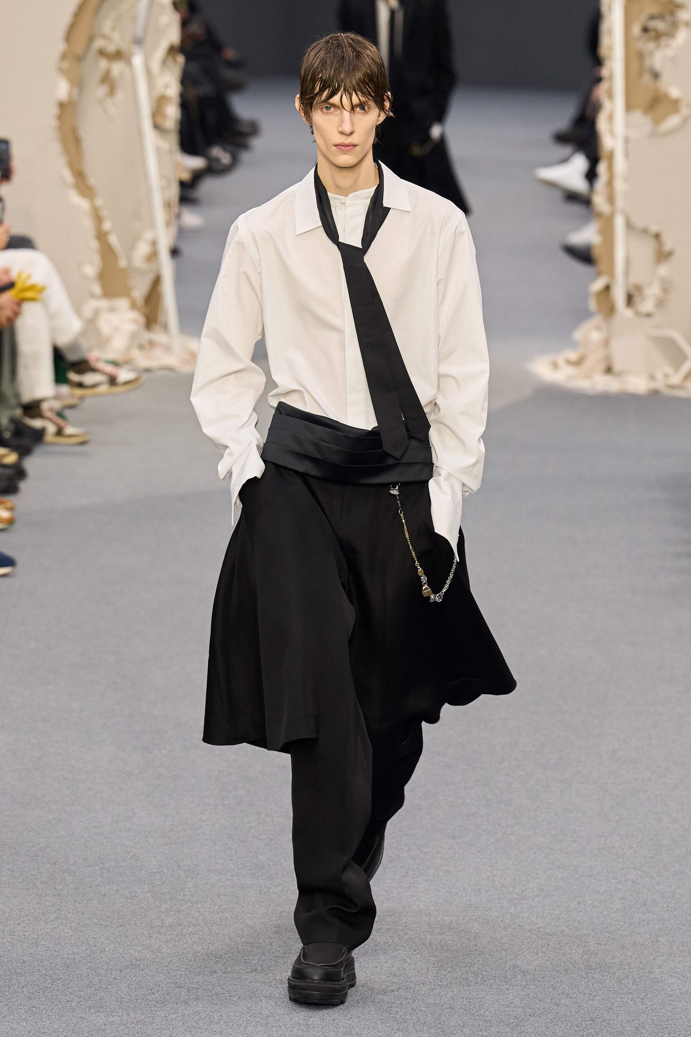 Sacai 2026秋冬再次展示其无可复制的“混合美学”。正装、牛仔、皮草与制服元素被高度结构化地拼接，形成既熟悉又陌生的服装形态。性别边界被进一步模糊，层叠结构制造流动节奏，使行走本身成为设计的一部分。系列在秩序与混乱之间找到平衡，是Sacai 对当代复杂生活状态的持续回应-顽石频道趋势研究